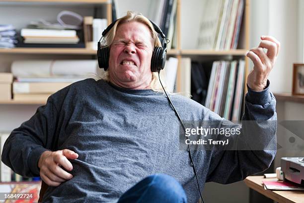 man pretends to play guitar listening to music - rockmuziek stockfoto's en -beelden