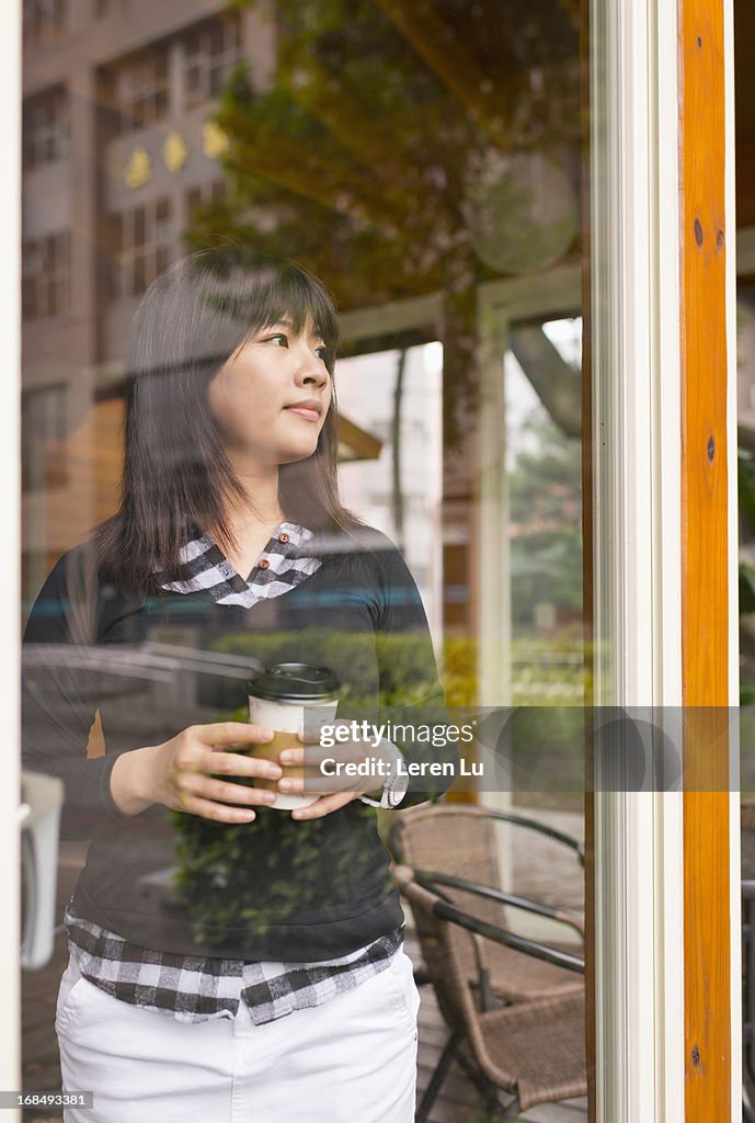 Young woman stands behide glass