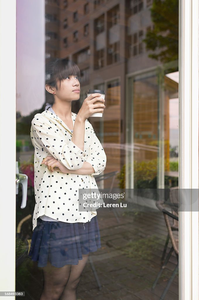 Young woman stands behide glass