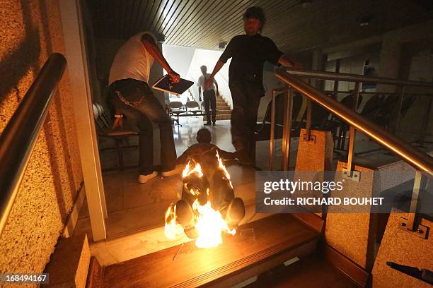 Man lies as he is engulfed in flames after he set himself on fire on May 10, 2013 at the Champ-Fleuri courthouse in the Saint-Denis de la Reunion, on...