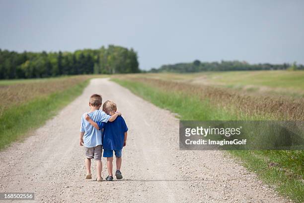 two cute preschool boys walking down the road - arms around stockfoto's en -beelden