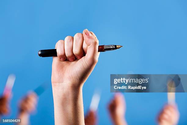 hand holding up fountain pen, more similar hands in background - penna bildbanksfoton och bilder