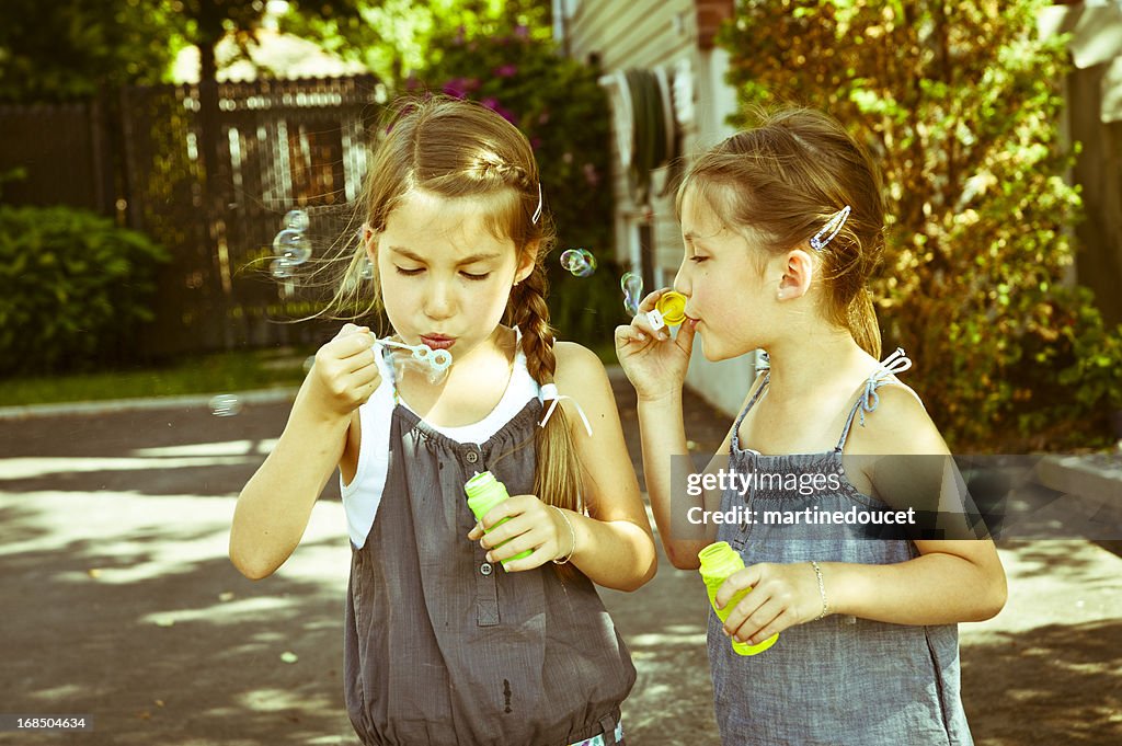Non identical twins blowing soap bubbles.