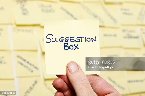 man's hand taking note "suggestion box" from wall of buzzwords - ideeënbus stockfoto's en -beelden