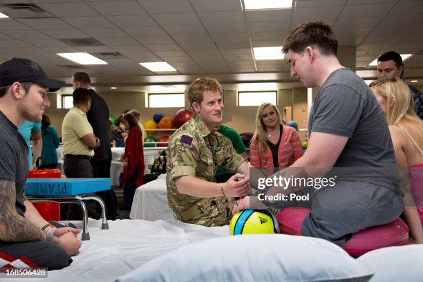 Prince Harry speaks with Staff Sgt. Timothy Payne , who lost his legs in an IED explosion in Afghanistan during his visit to the Military Advanced...