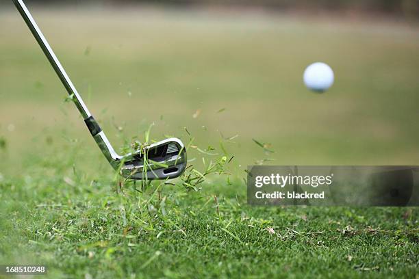 golf club hits ball in the air with grass flying - golfclub stockfoto's en -beelden
