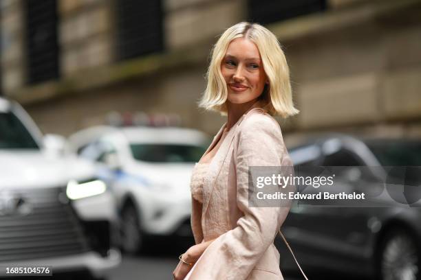 Meredith Duxbury wears a pale pastel pink look, an oversized blazer jacket with slit flared sleeves, a bras with embroidery, a mini skirt, outside...