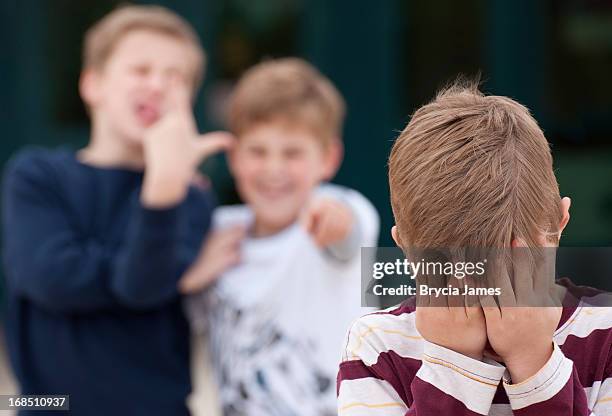 elementary student hides his face while being bullied - pest stockfoto's en -beelden