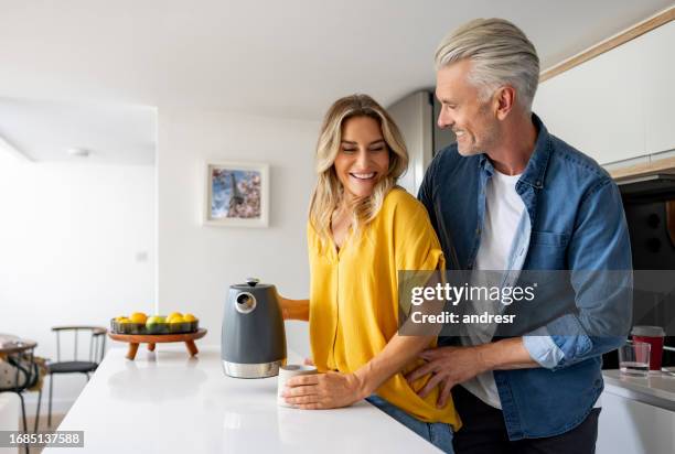 happy couple at home making a cup of coffee - warme dranken stockfoto's en -beelden