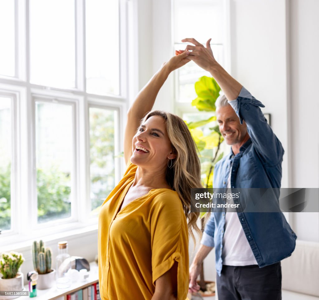 Happy couple dancing together at home