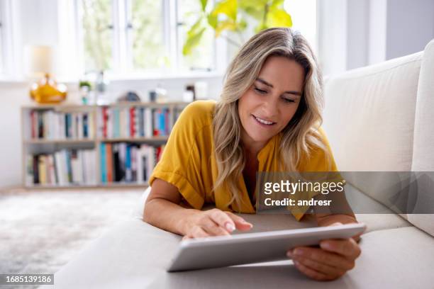 happy woman at home using a digital tablet - logic vs emotion stock pictures, royalty-free photos & images