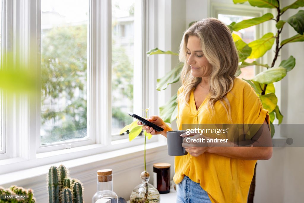 Woman looking at social media on her cell phone while drinking coffee
