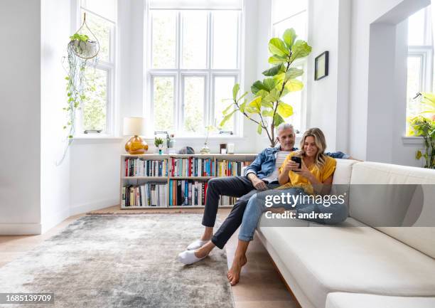 happy couple looking at social media on their cell phone - thier stock pictures, royalty-free photos & images