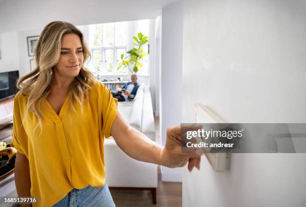 frau stellt die temperatur ihres hauses mit einem dimmer ein - dimmer stock-fotos und bilder