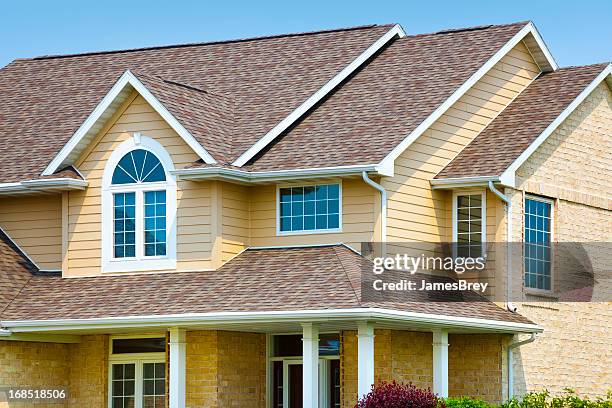 house with brick, architectural vinyl siding, asphalt shingle roof - dakgoot stockfoto's en -beelden