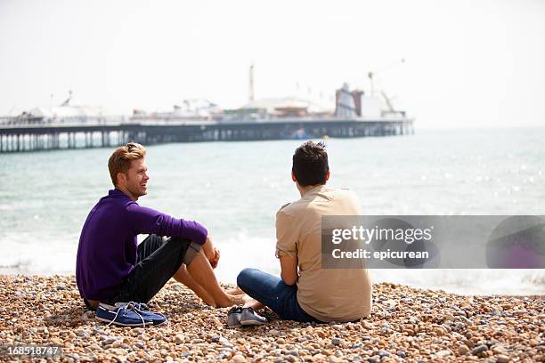 gay masculino casal sentado na praia de brighton - brighton beach england - fotografias e filmes do acervo