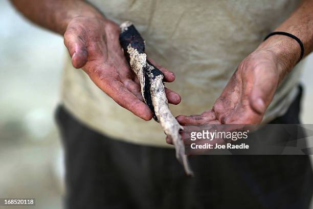 Archaeologist Mike Grady, with the Archaeological and Historical Conservancy, holds a tool made from the center spiral of a conch shell during an...