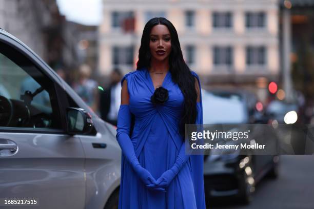 Fashion Week guest is seen wearing a sleeveless blue maxi dress with V-neck and a black rose at the neckline and matching blue long gloves during...