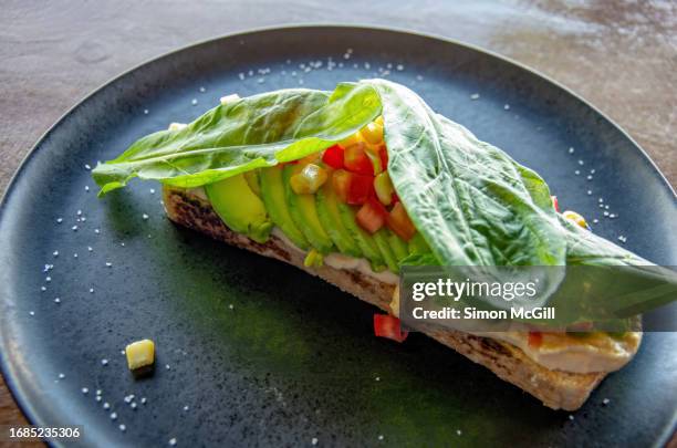avocado toast with hummus, sweet corn kernels, chopped tomato and romaine lettuce leaves on a plate - sanduíche aberta imagens e fotografias de stock