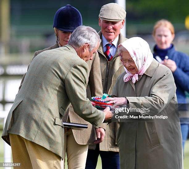 Queen Elizabeth II hands her stud groom Terry Pendry her rosettes after her horse Barbers Shop won the Tattersalls & Ror Thoroughbred Ridden Show...