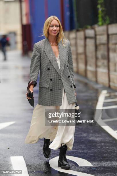Lisa Aiken wears a gray oversized blazer jacket, a white long slit dress, black leather ankle boots, outside Ulla Johnson, during New York Fashion...