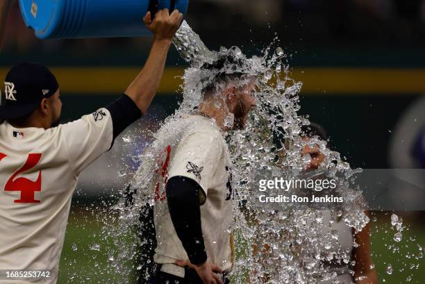 Jonah Heim of the Texas Rangers is doused with ice water by teammate Martin Perez following the team's 2-0 win over the Seattle Mariners at Globe...