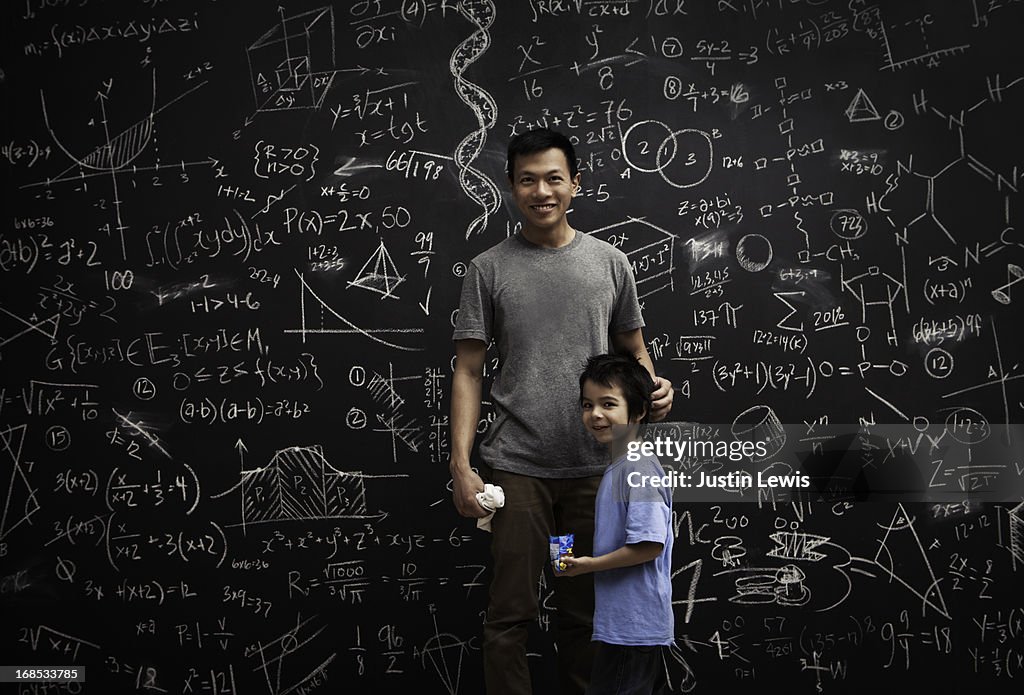 Dad and son in front of math covered chalkboard