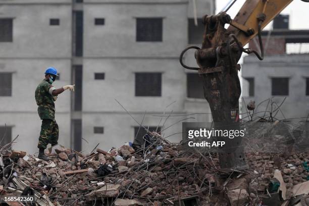 Bangladeshi Army official gestures as he guides an excavator operator to removes debris as they continue the second phase of the rescue operation...