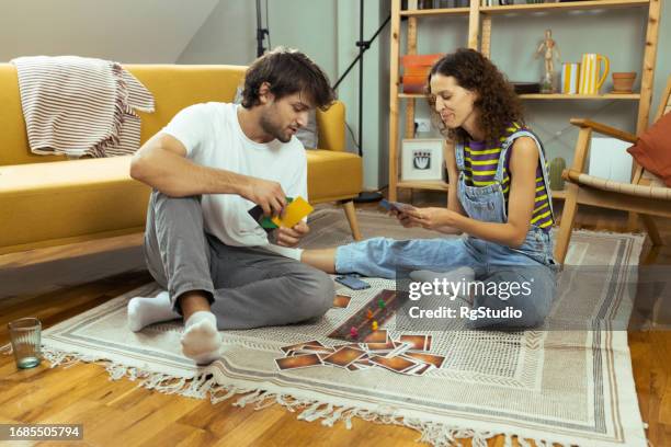 giovane coppia che gioca a un gioco da tavolo e si diverte - carte da gioco foto e immagini stock