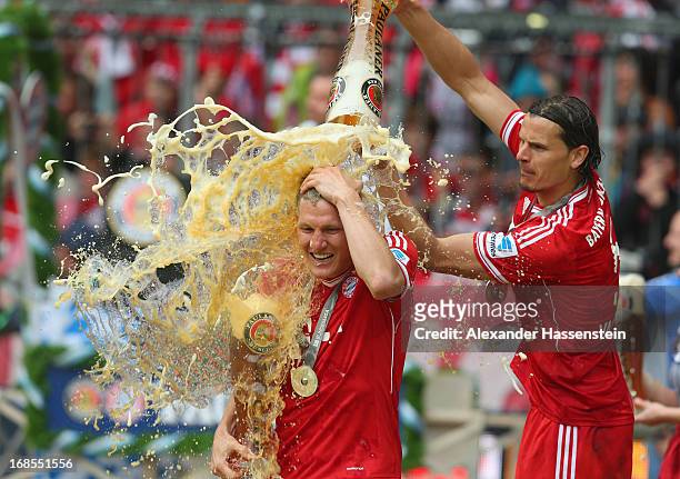 Bastian Schweinsteiger of FC Bayern Muenchen is drenched in beer by team-mate Daniel van Buyten following their match against Augsburg at the Allianz...