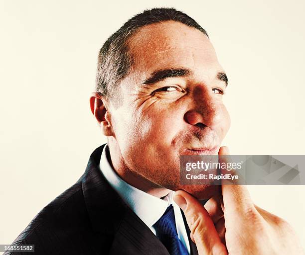 sneaky-looking businessman smiles to himself in triumph - suspicion stock pictures, royalty-free photos & images