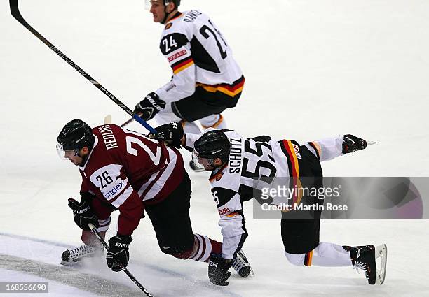 Felix Schuetz of Germany and Krisjanis Redlihs of Latvia battle for the puck during the IIHF World Championship group H match between Germany and...