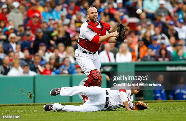 David Ross of the Boston Red Sox throws a bunted ball over teammate Will Middlebrooks of the Boston Red Sox during the game on May 11, 2013 at Fenway...