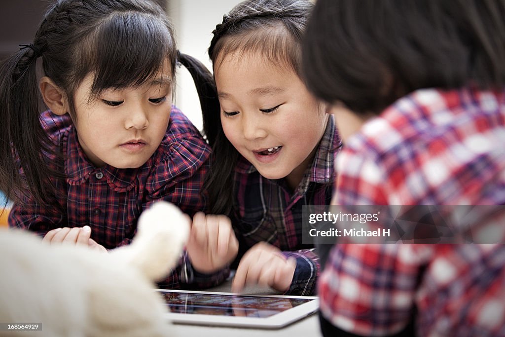 Small kids playing with a digital tablet.