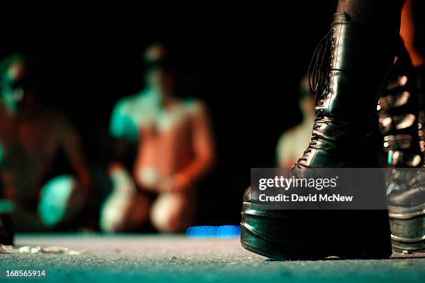 The boots of a dominatrix are seen as men and woman in a contest to be the best submissive kneel at a dungeon party during the domination convention,...