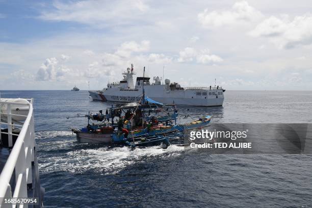 This photo taken on September 22, 2023 shows Philippine fishing motherboat "Moises" sailing past a Chinese coast guard ship after the former was...