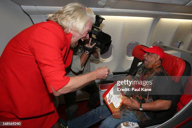 Sir Richard Branson tips a tray of drinks onto Tony Fernandes prior to their flight to Kuala Lumpur at Perth International Airport on May 12, 2013 in...