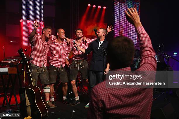 Bastian Schweinsteiger of Bayern Muenchen performes with his team mates Arjen Robben, Thomas Muellern and singer Marlon Roudette live on stage during...