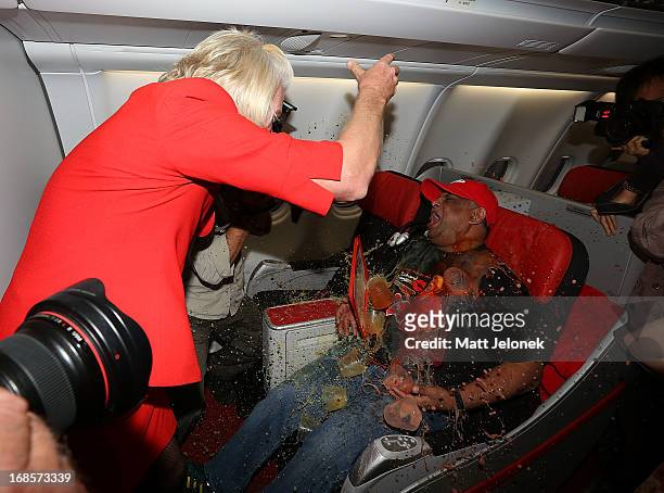 Sir Richard Branson pours drinks on AirAsia CEO Tony Fernandes on board a flight to Kuala Lumpur at Perth International Airport on May 12, 2013 in...