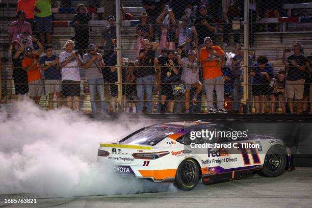 Denny Hamlin, driver of the FedEx Freight Direct Toyota, celebrates with a burnout in front of fans after winning the NASCAR Cup Series Bass Pro...