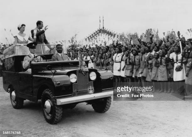 Queen Elizabeth II and Prince Philip wave from an open Land Rover to a crowd of schoolchildren at a rally held at a racecourse in Ibadan, Nigeria,...