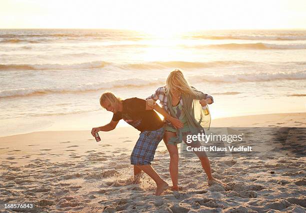 man and woman wrestling on the beach - friend mischief stock pictures, royalty-free photos & images