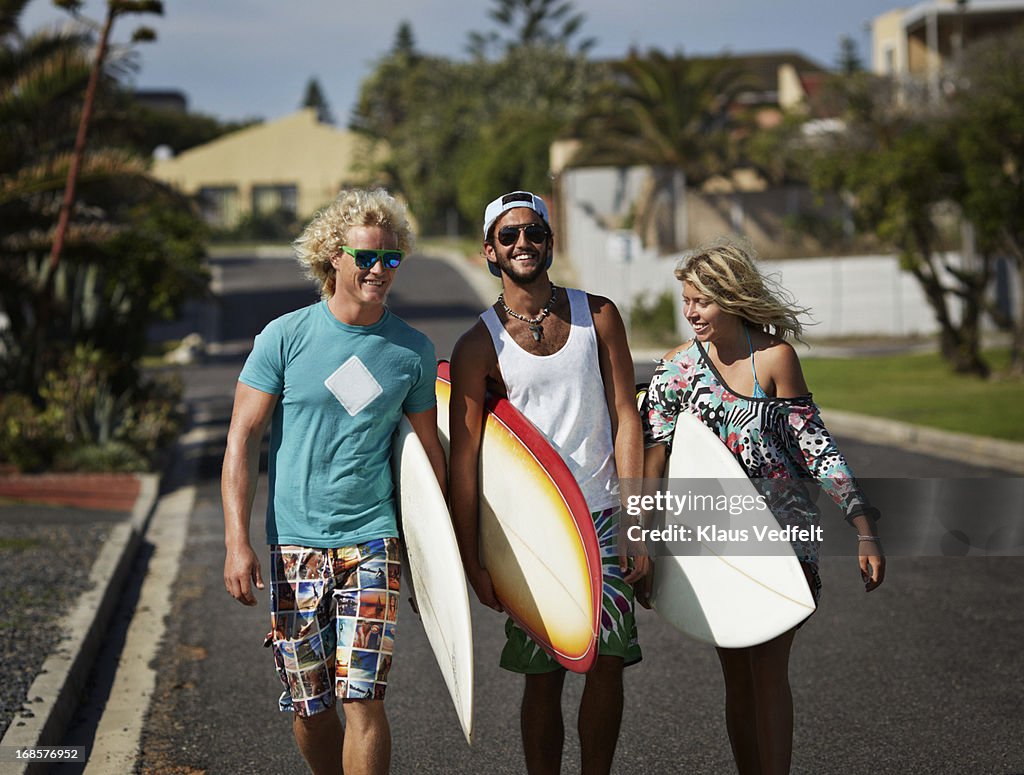 Surfers walking with boards laughing