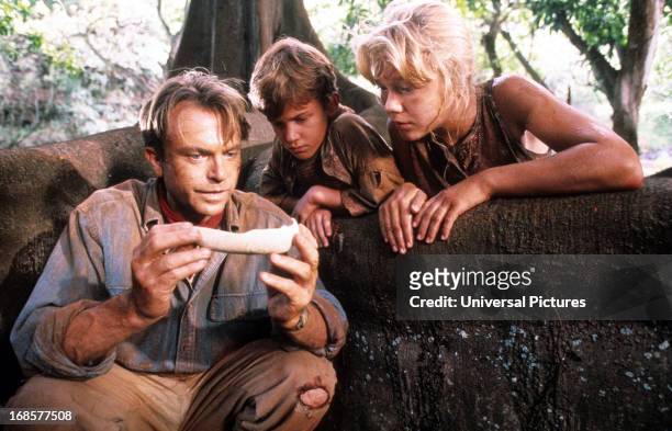 Sam Neill shows a bone to Joseph Mazzello and Ariana Richards in a scene from the film 'Jurassic Park', 1993.