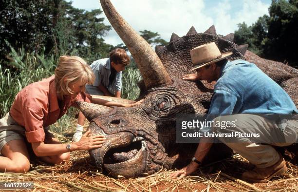 Laura Dern and Sam Neill come to the aid of a triceratops in a scene from the film 'Jurassic Park', 1993.