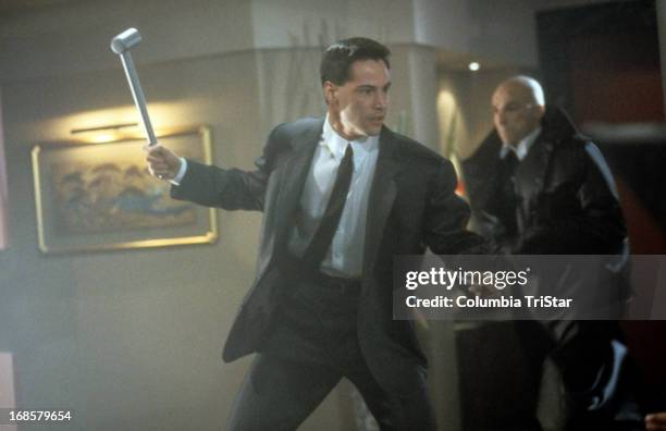 Keanu Reeves swings a metal rod in a scene from the film 'Johnny Mnemonic', 1995.