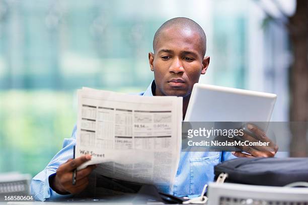 investor compares quotes from newspaper and tablet - black stock trader stock pictures, royalty-free photos & images