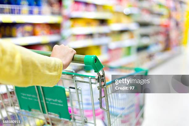 closeup of  woman's hands pushing a shopping cart - shopping trolleys stockfoto's en -beelden