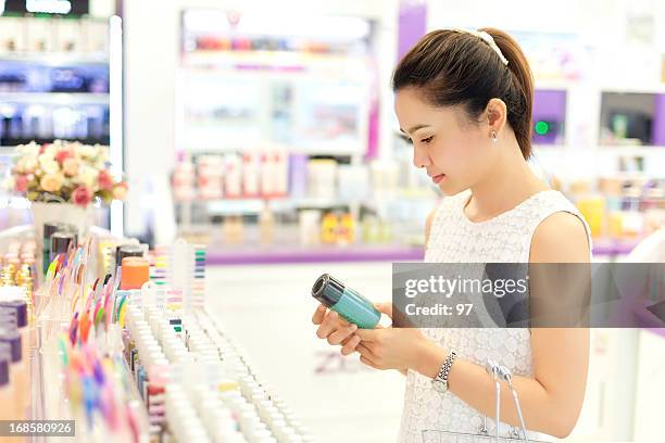 asiatique femme shopping dans le magasin d'élaborer des produits cosmétiques. - magasin cosmétique photos et images de collection