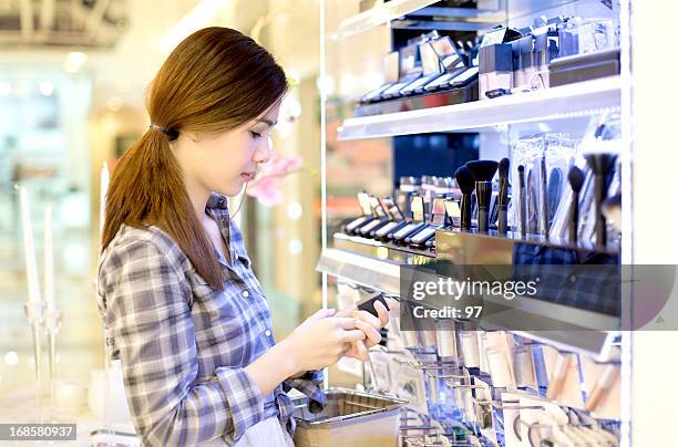 asiatique femme shopping dans le magasin d'élaborer des produits cosmétiques. - magasin cosmétique photos et images de collection